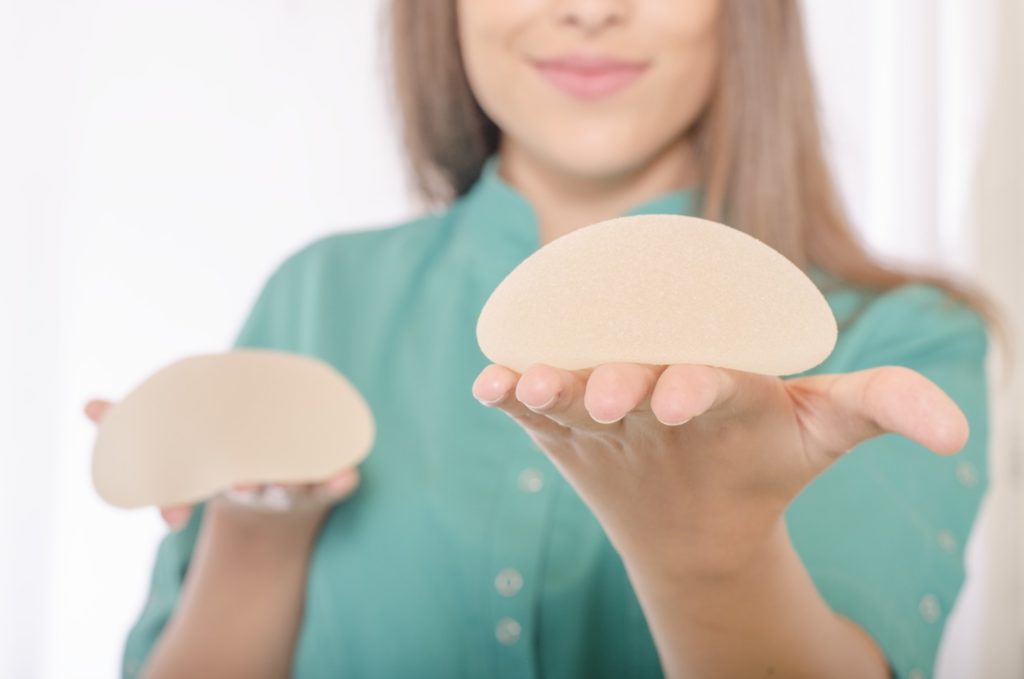 Women holding different size breast implants